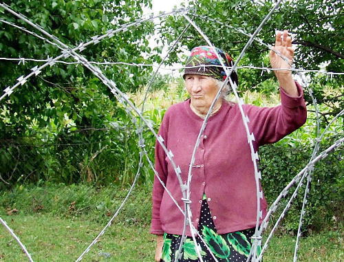 Валя  Ванишвили у колючей проволоки, которая отделила ее  дом от остальных. Село Диди Хурвалети Горийского района Грузии, июль 2013 г. Фото Эдиты Бадасян для "Кавказского узла"