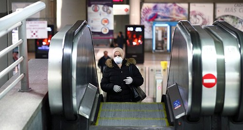 Женщина в медицинской маске на эскалаторе. Фото: REUTERS/Sergio Perez